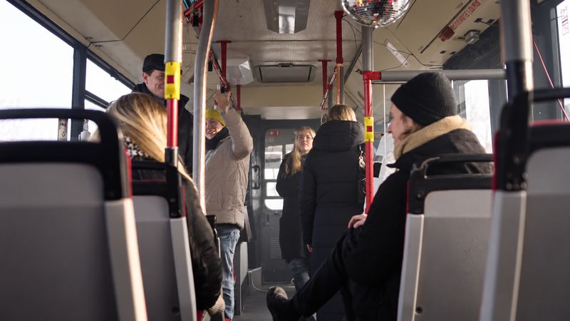 Visitors standing and sitting inside the bus, a mirror ball hanging from the ceiling