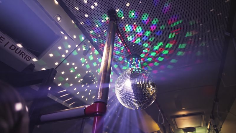 A mirror ball scattering coloured spots of light across the bus ceiling