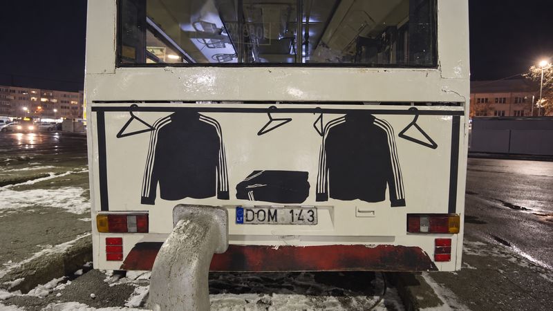 The back of the bus at night, with a graphic of tracksuit jackets on hangers