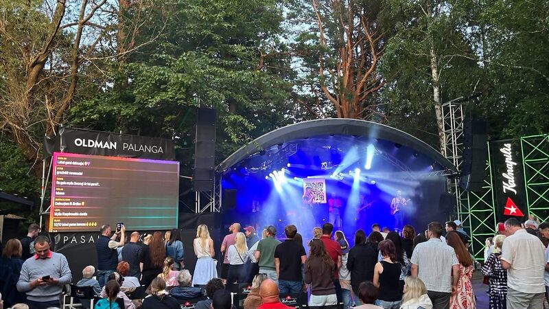 An open-air concert: the audience’s messages on a large LED screen beside the stage, and a QR code on the stage